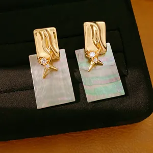Detailansicht der irisierenden Muschelstruktur und des Sterndesigns auf Ohrsteckern