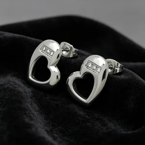 Detail view of silver heart stud earrings with sparkling stone inlay on black velvet