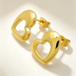 Detailed macro view of polished gold hollow heart stud earrings made of titanium steel.