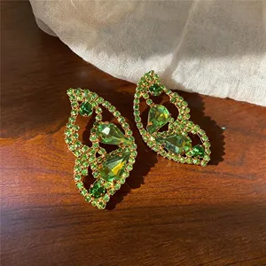 Detailansicht eleganter grüner Strass-Ohrringe in Schmetterlingsform auf Holzoberfläche