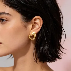 Close-up view showing the detail of a golden hollow heart stud earring with diamonds