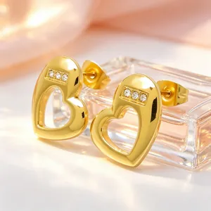 Close-up detail of gold titanium steel heart stud earrings with sparkling crystals