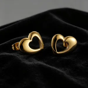 Detailed macro view of polished gold-plated hollow heart stud earrings on black velvet