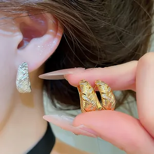 Detailopname van geometrische getextureerde oorringen met zirkonia in goud en zilver