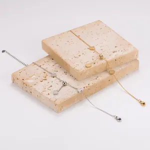 Detailopname van minimalistische hartjesarmbanden in goud en zilver op stenen blokken.