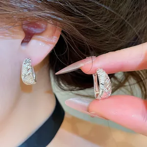 Close-up van elegante zilveren oorbellen met geometrische textuur en glanzende zirkonen