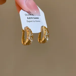 Gedetailleerde macro-weergave van gouden oorringen met geometrische texturen en zirkoon