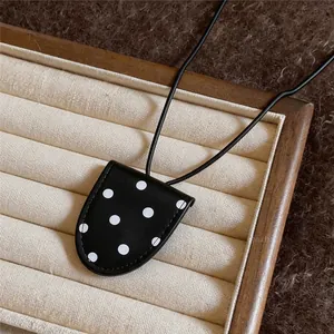 Detail of a black leather glasses clip necklace with stylish white polka dots.