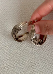 Primo piano di orecchini a cerchio intrecciati color oro dalla texture elegante
