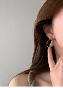 Primo piano di eleganti orecchini a cerchio dorati a strati su una modella per un look vintage.