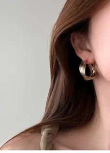 Orecchini a cerchio multistrato in oro cioccolato indossati da una modella donna.