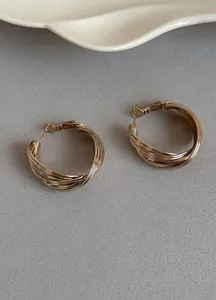 Vista dettagliata di orecchini a cerchio intrecciati in oro cioccolato con design in metallo.