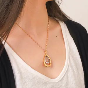 Nahaufnahme einer Halskette mit gold-silbernem Hohl-Tropfen-Anhänger aus Edelstahl am Modell