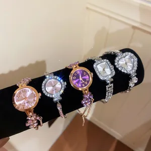 Detailed view of five rhinestone-encrusted women's jewelry watches on a black stand.