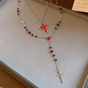 Gros plan d'un ensemble de colliers avec pendentifs croix et perles de résine rouges