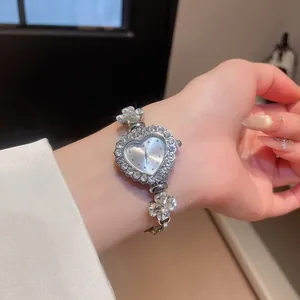 Close-up of a sparkling rhinestone heart-shaped watch with flower-detailed silver bracelet