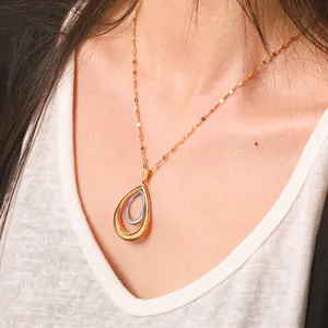 Detailansicht einer eleganten zweifarbigen Tropfenanhänger-Halskette an einem Modell