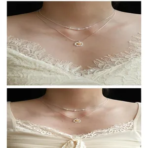 Dettaglio ravvicinato di una collana a due strati con ciondolo a fiore in zircone e perle