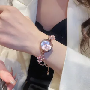 Close-up of rose gold watch with crystal flower charms and diamond accents on wrist