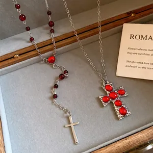Détail d'un ensemble de colliers avec pendentifs croix gothique et pierres en résine rouge