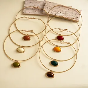 Vintage gouden halskettingen met kleurrijke ovale hars hangers op stenen decoratie
