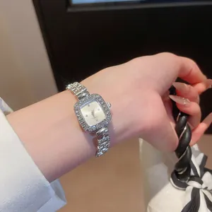 Detailed close-up showing an elegant silver rhinestone square watch on a woman's wrist