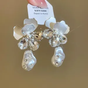 Detailaufnahme französischer Blumenohrringe mit funkelnden Kristallen und Perlen.