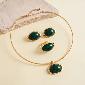 Detail van 3-delige vintage goudkleurige sieradenset met ovale groene harsstenen.