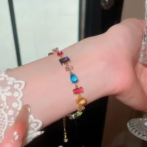 Detailansicht eines bunten Zirkonia-Armbands am Handgelenk mit eleganter Spitze.