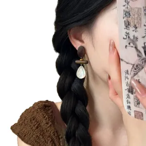 Elegant Bohemian retro wood and white shell teardrop drop earrings on female model