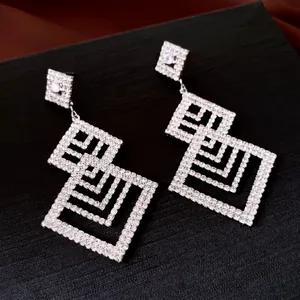 Silberne geometrische Hängeohrringe mit funkelnden Strasssteinen für einen luxuriösen Look.