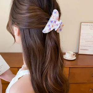 Detalle de pinza para el pelo de acrílico blanco con estampado floral morado y naranja en el pelo