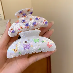 Vista detallada de dos pinzas para el cabello de acrílico con motivos de flores y mariposas