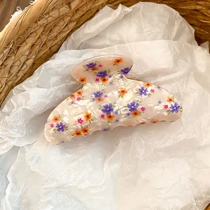 Vista detallada de una pinza para el cabello de acrílico con motivos florales.