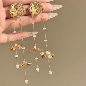 Detail view of gold flower tassel earrings with delicate beads and metallic shine.