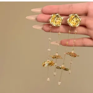 Exquisite gold metal flower tassel earrings with beads held by hand for detail