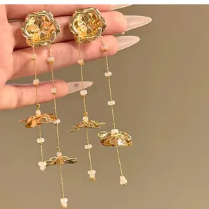 Detailed close-up of elegant gold metal flower tassel earrings with delicate pink beads