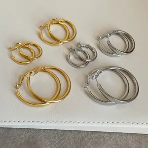 Detailansicht von minimalistisch polierten Gold- und Silber-Creolen in drei verschiedenen Größen