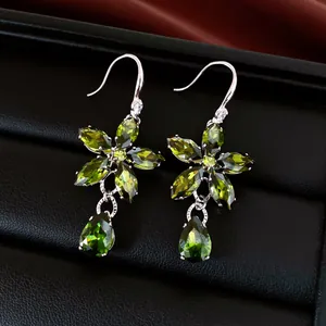 Détail de boucles d'oreilles fleurs vintage en argent avec pierres de zircon vert