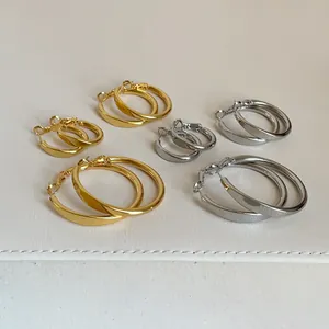 Detailansicht minimalistischer Gold- und Silber-Creolen in drei Größen auf weißem Leder