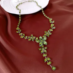 Gros plan détaillé d'un collier de fleurs en zircon vert sur fond de soie rouge luxueux