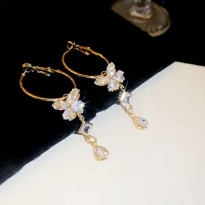 Exquisite close-up of sparkling gold butterfly hoop earrings with dangling zircon tassels