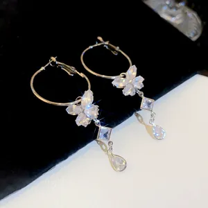 Close-up of sparkling zircon butterfly and teardrop charms on silver hoop earrings