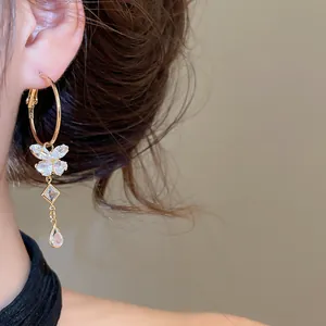 Detailed close-up shot of sparkling zircon butterfly tassel hoop earrings on a model