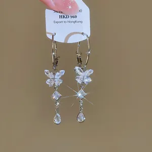 Detailed macro view of sparkling zircon butterfly tassel hoop earrings in silver finish
