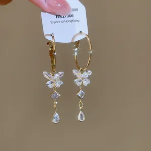 Close-up detail of luxury sparkly zircon butterfly tassel hoop earrings in golden finish