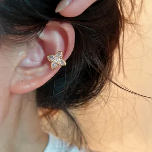Macro view of a gold-plated flower ear cuff with sparkling zircons worn on the cartilage