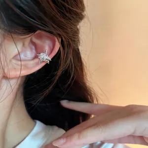 Detail shot of a sparkling zircon star ear cuff worn on a model's ear for fashion