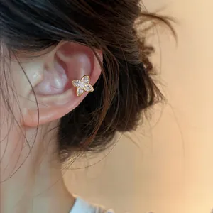 Macro view of sparkling zircon four-petal flower ear cuff on person's ear