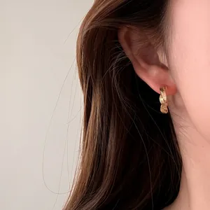 Elegante minimalistische goldene gedrehte Creolen von einem Model getragen für den Alltag